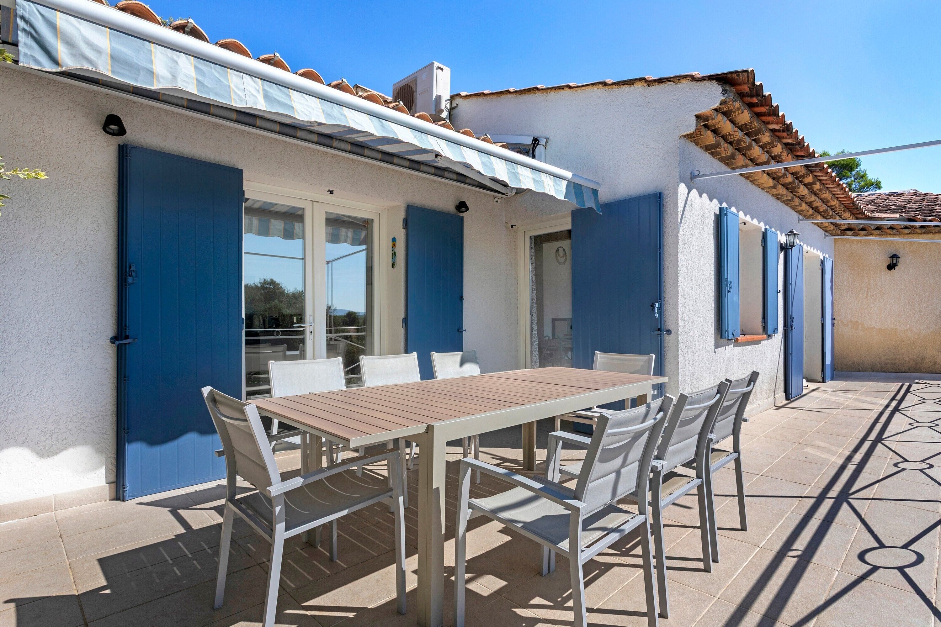 Une terrasse avec une table et des chaises, une porte bleue et un sol carrelé.