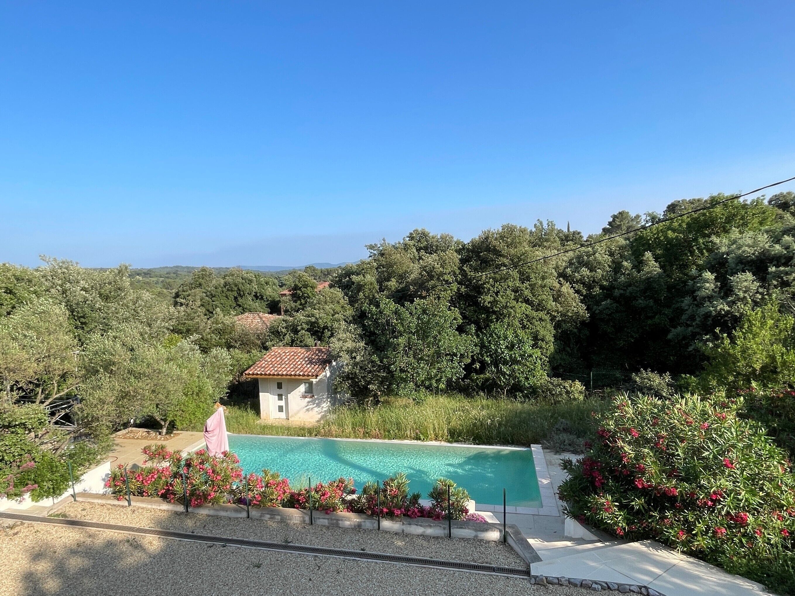 Une propriété résidentielle dotée d’une piscine, entourée d’une végétation luxuriante et offrant une vue dégagée sur le paysage.