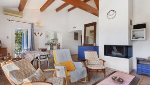 A spacious living area with wooden beams, a fireplace, and a dining area with a view.
