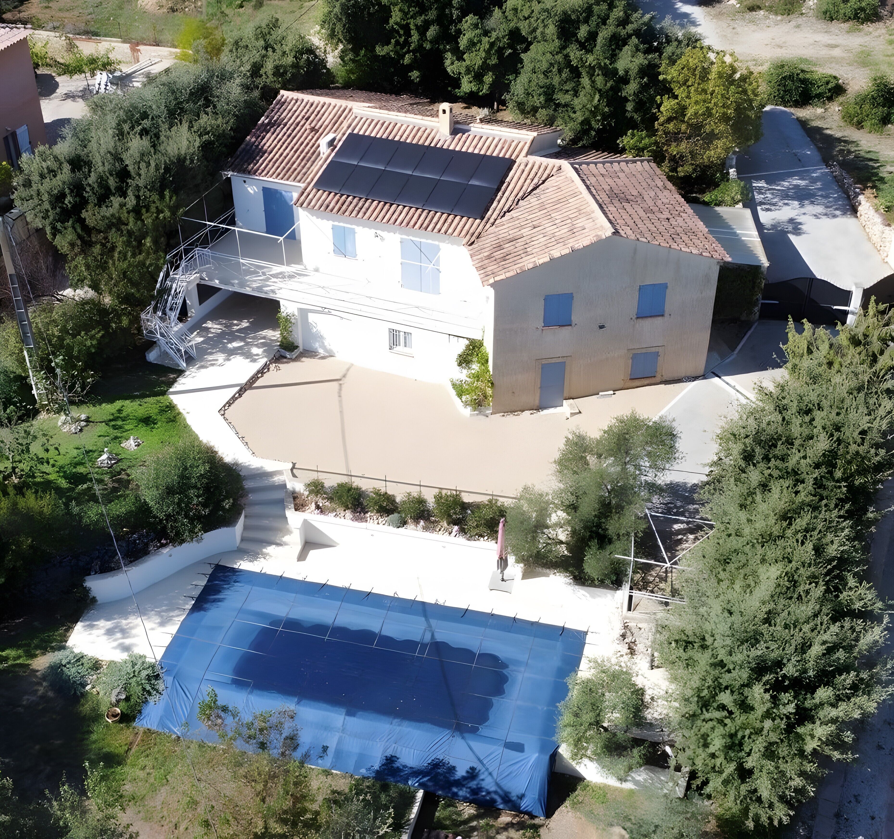 A house with a swimming pool, a covered outdoor area, and a garden.