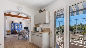 A kitchen with a microwave, toaster, and cabinets, leading to a dining area with chairs and a table.