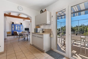 A kitchen with a microwave, toaster, and cabinets, leading to a dining area with chairs and a table.