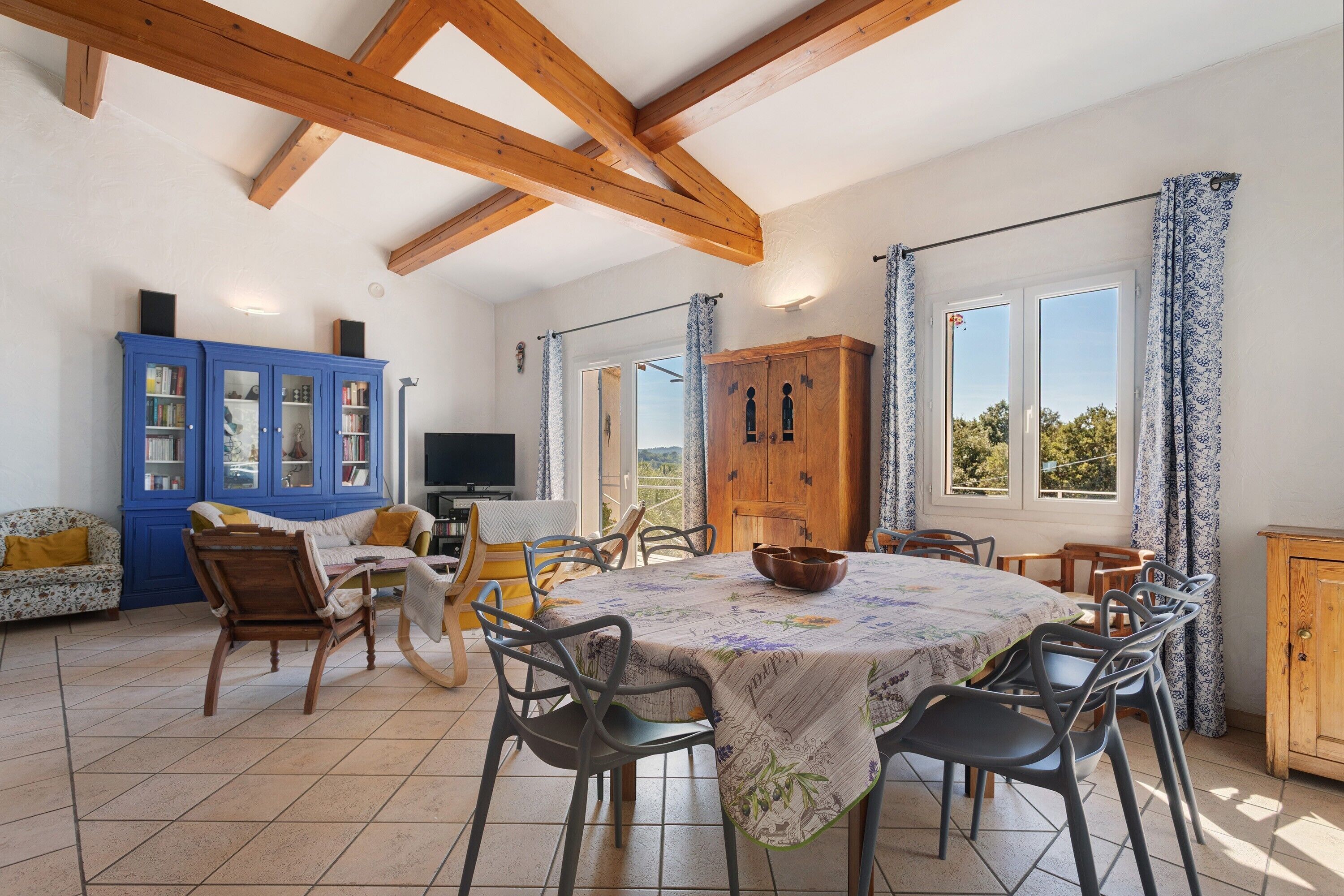 A dining area with a round table, chairs, and a blue cabinet.