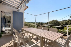 An outdoor patio with a table and chairs, a view of the countryside, and a blue wall. - Holiday Home 'Les Loriots' with Private Pool, Wi-Fi, and Air Conditioning (Flassans-sur-Issole)