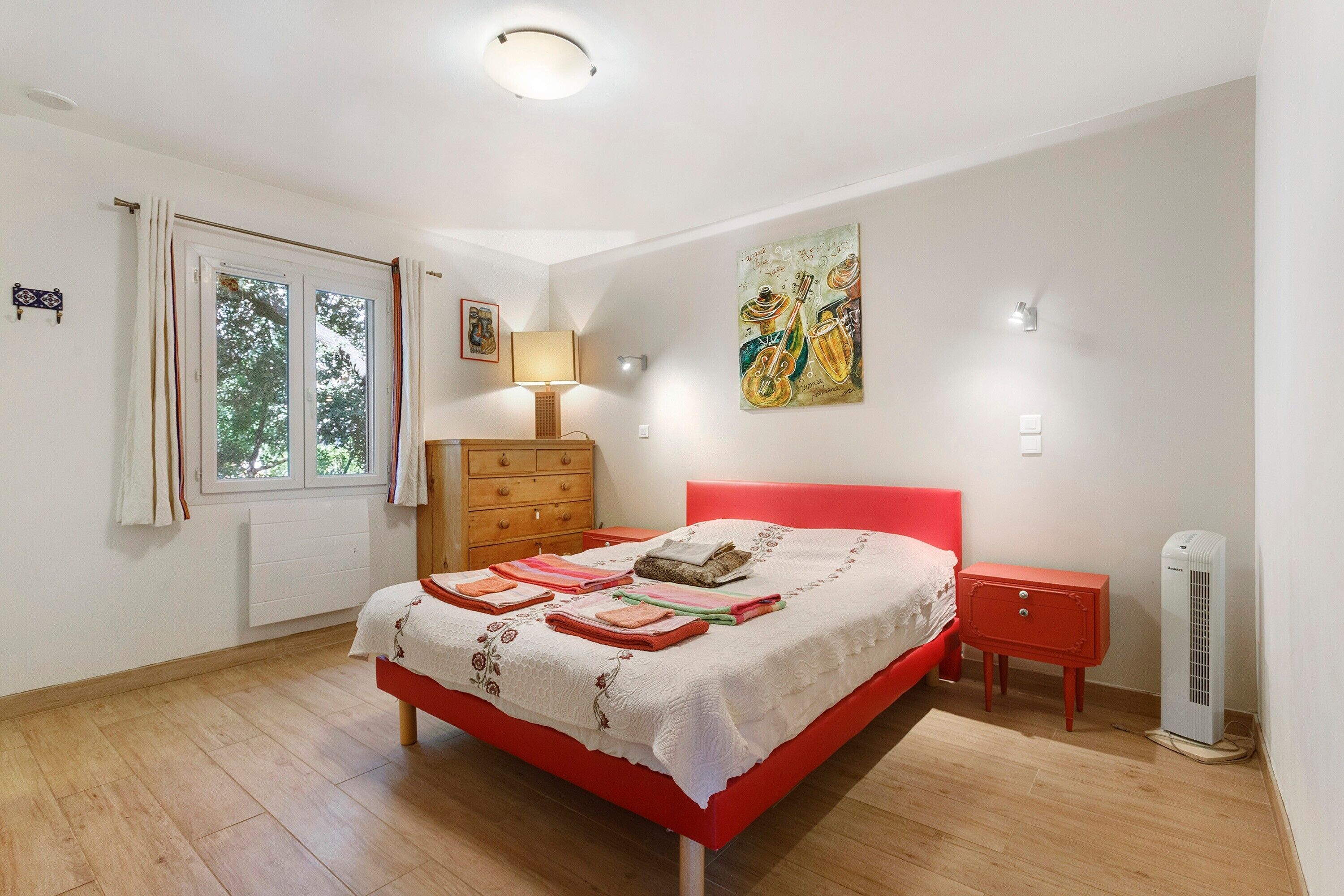 Ein Schlafzimmer mit einem roten Bett, einem Holzschrank und einer Heizung.