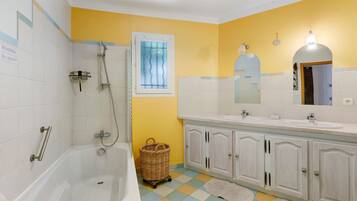 Une salle de bain avec une baignoire, une douche, un lavabo et un miroir.