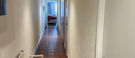 A hallway with a tiled floor, a radiator, and a door on the right.