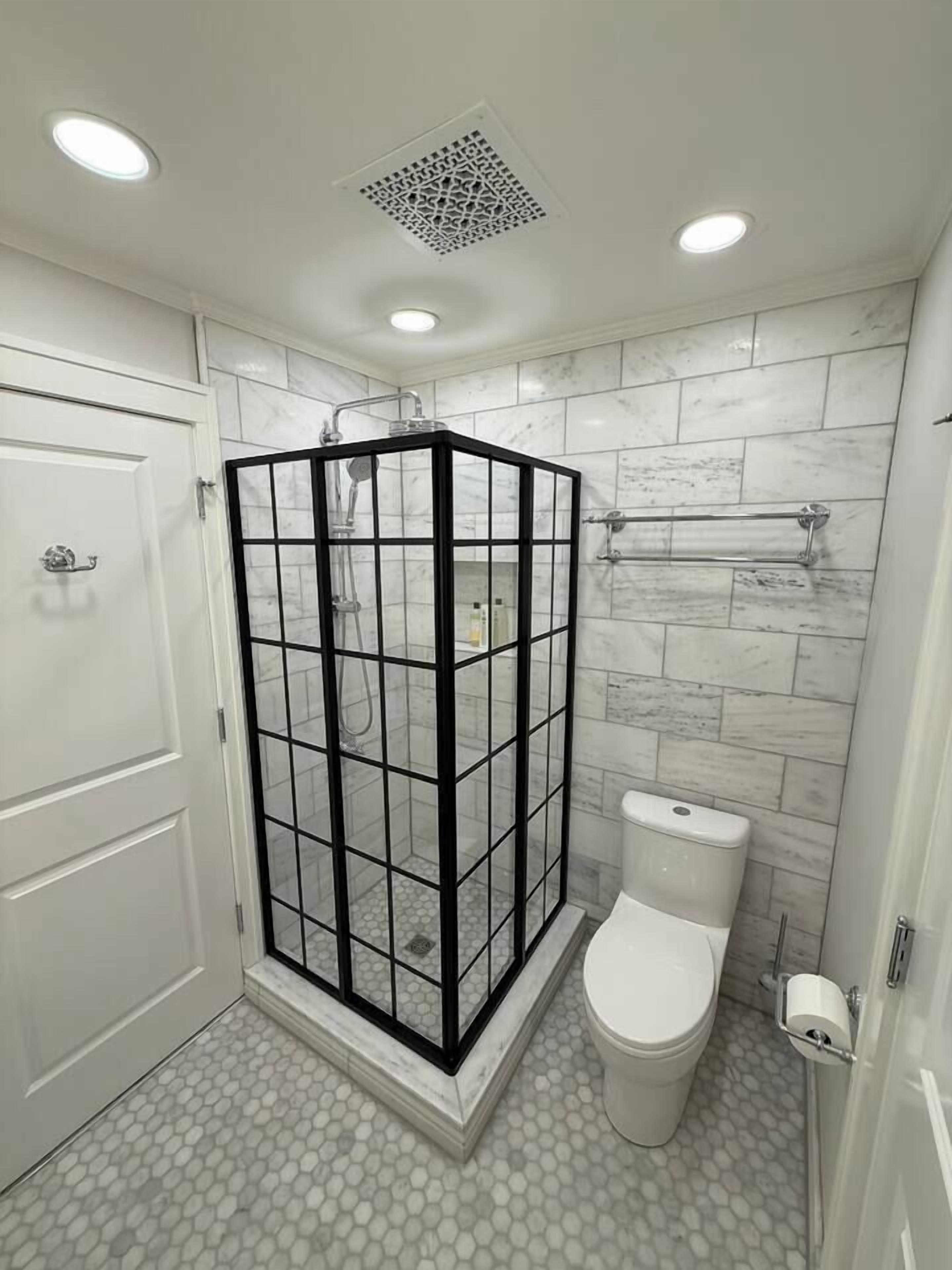 A bathroom with a glass-enclosed shower, a toilet, and tiled walls.