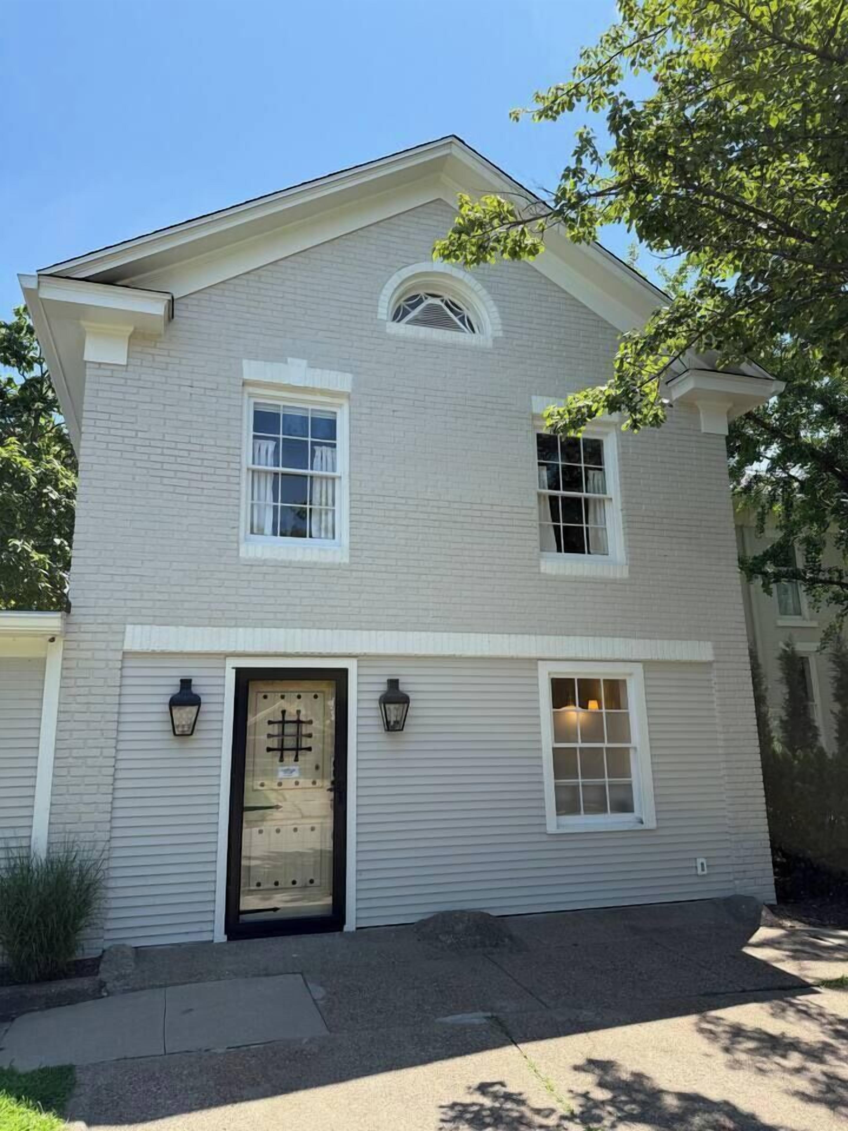 A two-story house with a symmetrical facade, a central entrance with a door, and two windows on the upper floor.