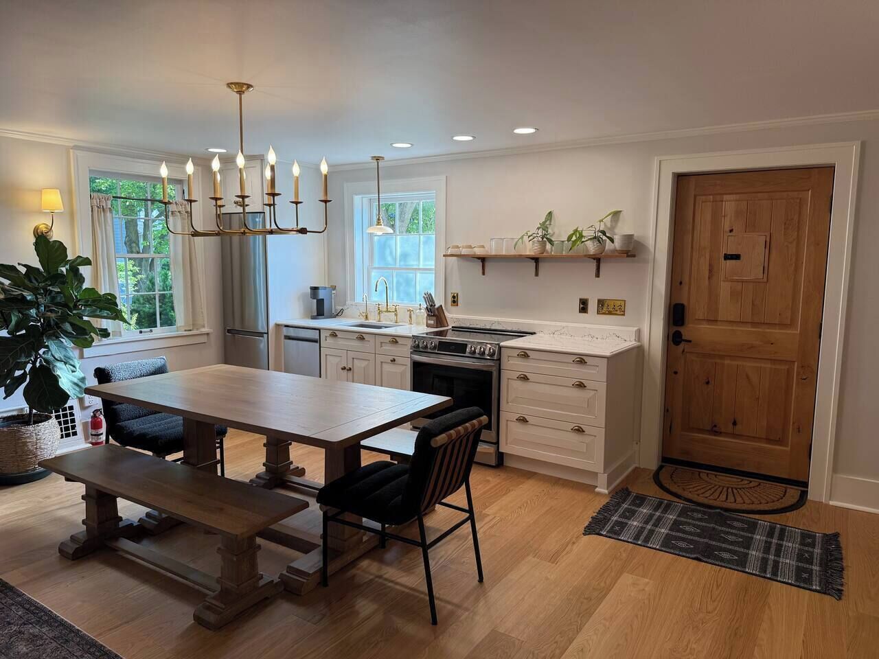 Une cuisine moderne avec une table à manger en bois, des meubles de rangement blancs et un four encastré.