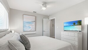A bedroom with a bed, a TV on a dresser, and a painting on the wall. - Paradise on Pearl 2-bedroom bungalow at Englewood Beach (Englewood)