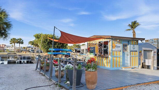 A waterfront restaurant with outdoor seating, a boat rental sign, and a small building with colorful vertical stripes. - Paradise on Pearl 2-bedroom bungalow at Englewood Beach (Englewood)