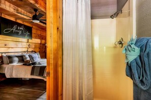 A wooden cabin interior with a bed, a shower area, and a sign that reads 'Always You'. - Romantic - Firepit - Hot tub - Pet Friendly (Sevierville)