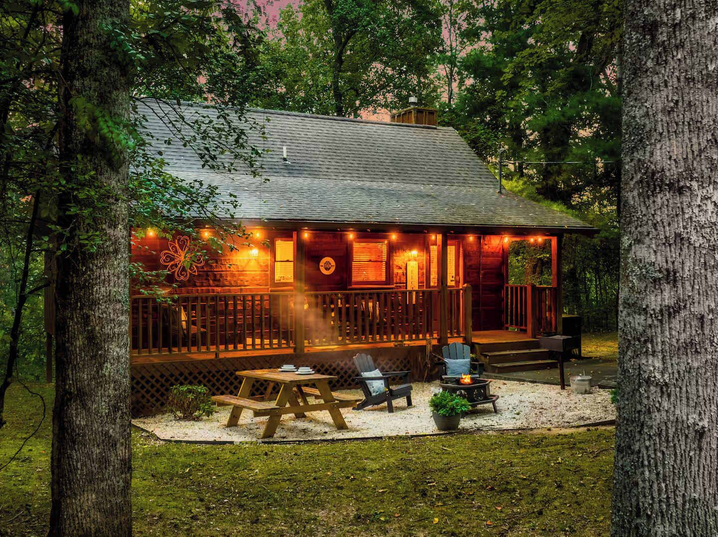 Eine Holzhütte mit Veranda, Sitzgelegenheit im Freien und einem Feuerkorb.