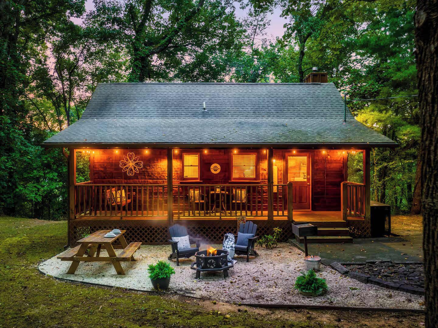 A wooden cabin with a porch, outdoor seating, and a fire pit.