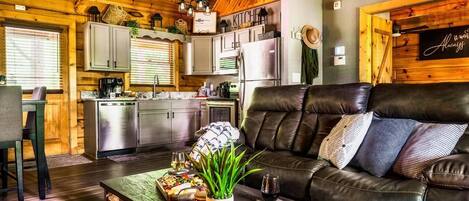 A cozy cabin interior with a dining area, a leather sofa, and a kitchen.