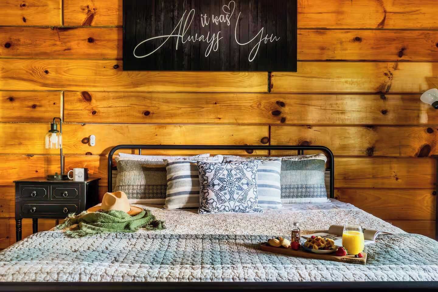 A neatly made bed with a quilt, pillows, and a tray of breakfast items.