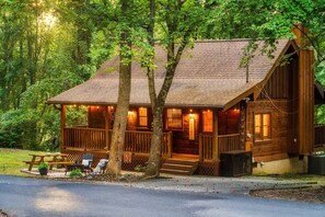 A wooden cabin with a porch, a welcome sign, and a picnic table. - Romantic - Firepit - Hot tub - Pet Friendly (Sevierville)