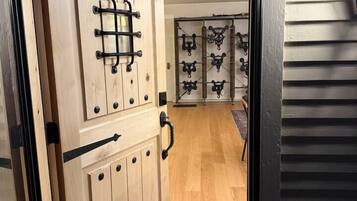A wooden door with a metal handle and a small window, leading to a room with a patterned rug and a curved mat.