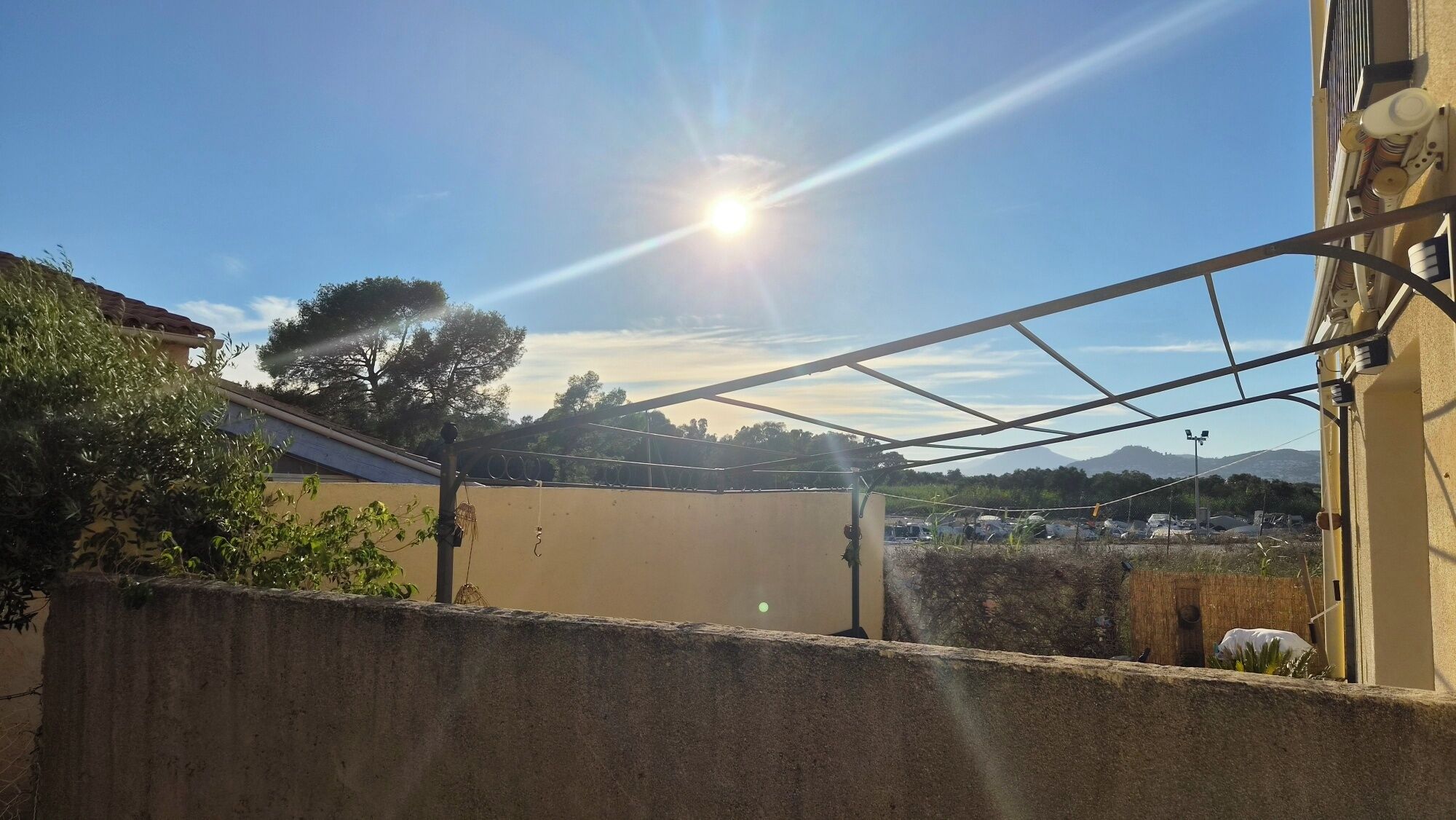 Klarer Himmel mit Sonnenschein, eine Metallkonstruktion und ein weiter Blick auf einen Parkplatz.