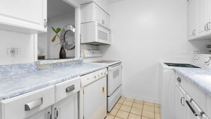 A kitchen with white cabinets, a stove, a microwave, and a sink. - Waikiki Beach Airbnb | Pool, Parking,Walk to Beach (Honolulu)