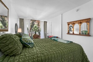 Une chambre à coucher avec un lit, un grand miroir et une vue sur l’extérieur.