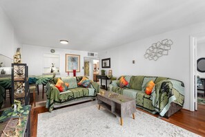 Uma sala de estar ampla com sofá, mesa de centro e um espaço de jantar com cadeiras e mesa.