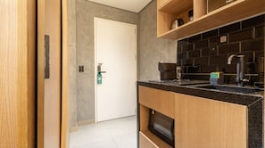 A modern kitchen with a black countertop, wooden cabinets, and a built-in oven. - Studio Perto da Av Paulista e Masp Jardim Paulista (São Paulo)