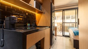 A compact kitchen with a modern design, a built-in microwave, and a coffee maker. - Studio Perto da Av Paulista e Masp Jardim Paulista (São Paulo)