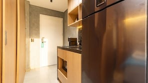 A modern kitchen with a stainless steel refrigerator, wooden cabinets, and a built-in oven. - Studio com Varanda a 200m da Paulista e do Masp (São Paulo)