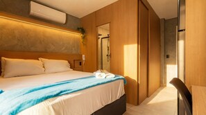 A modern hotel room with a large bed, a shower area, and a seating area. - Studio com Varanda a 200m da Paulista e do Masp (São Paulo)