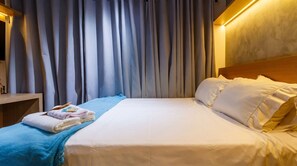 A hotel room with a neatly made bed, a bedside table with towels, and a curtain backdrop. - Studio Perto da Av Paulista e Masp Jardim Paulista (São Paulo)