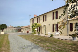A building with a gravel driveway leading to a gated entrance.