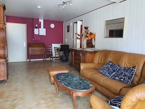 A living room with a brown leather sofa, a wooden coffee table, and a herringbone-patterned floor.