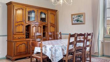 Une salle à manger avec un buffet en bois, une table recouverte d’une nappe et des chaises.