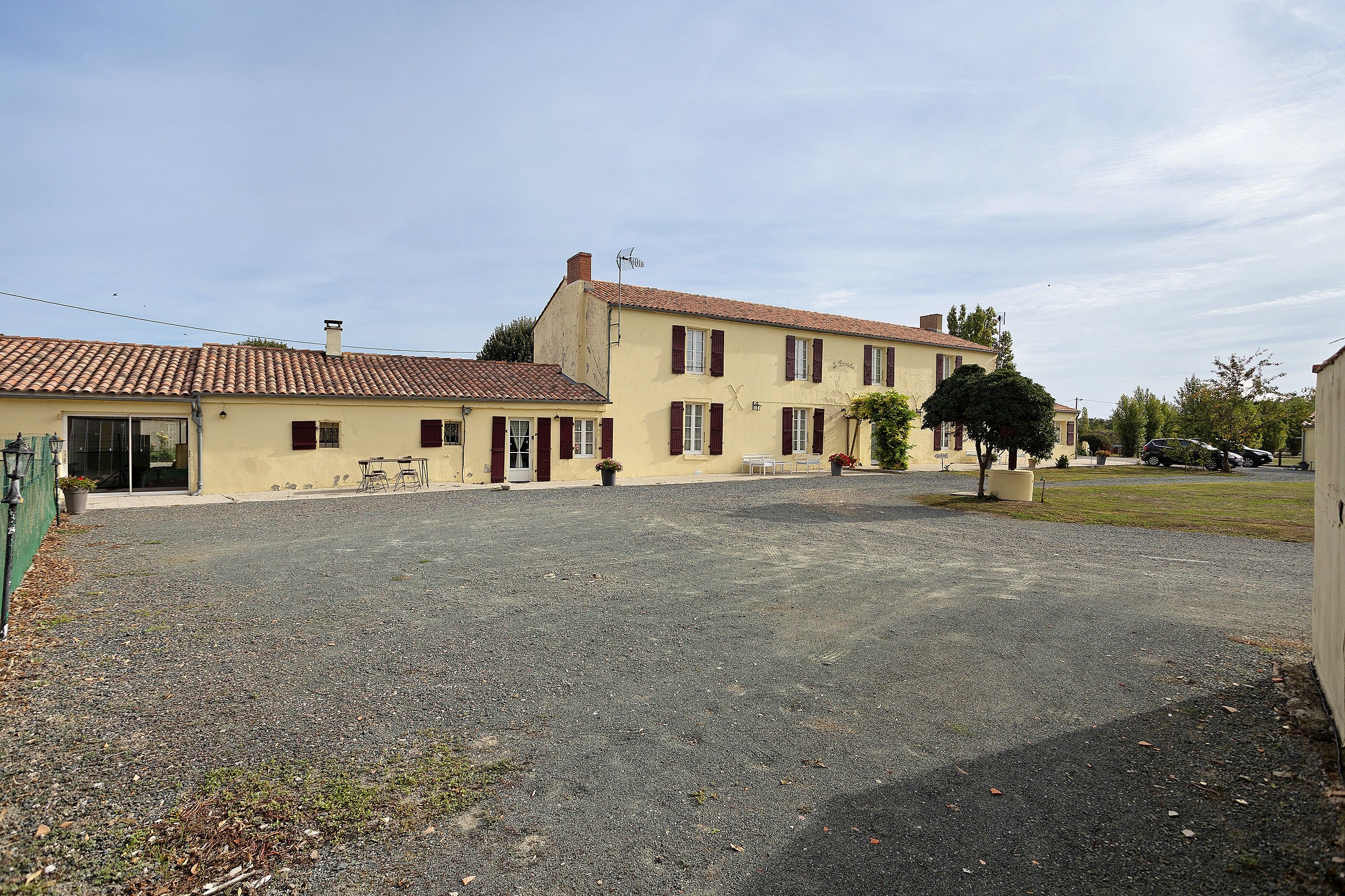 Un bâtiment à deux étages avec une allée gravillonnée et un petit jardin.
