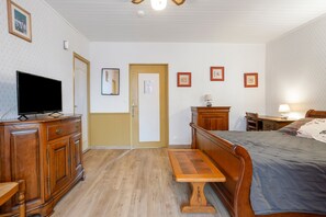 Habitació d'hotel amb un llit de fusta, una televisió damunt d'una petita taula, un escriptori amb una làmpada i una porta amb un mirall.