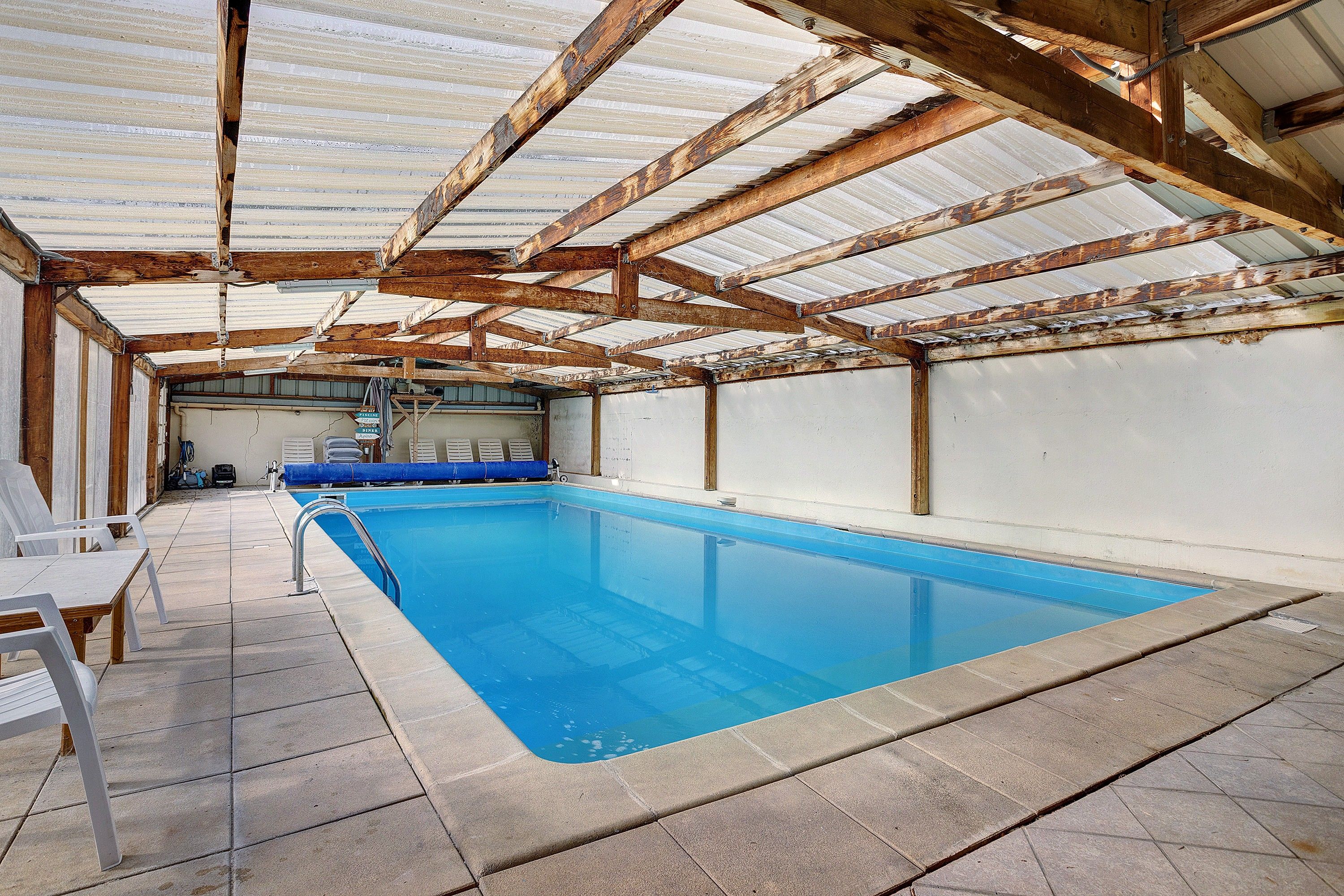 An indoor swimming pool with a tiled floor and a metal pool ladder.