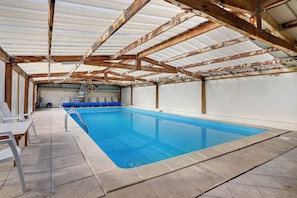 Una piscina interior con suelo de baldosas y escalera de metal.