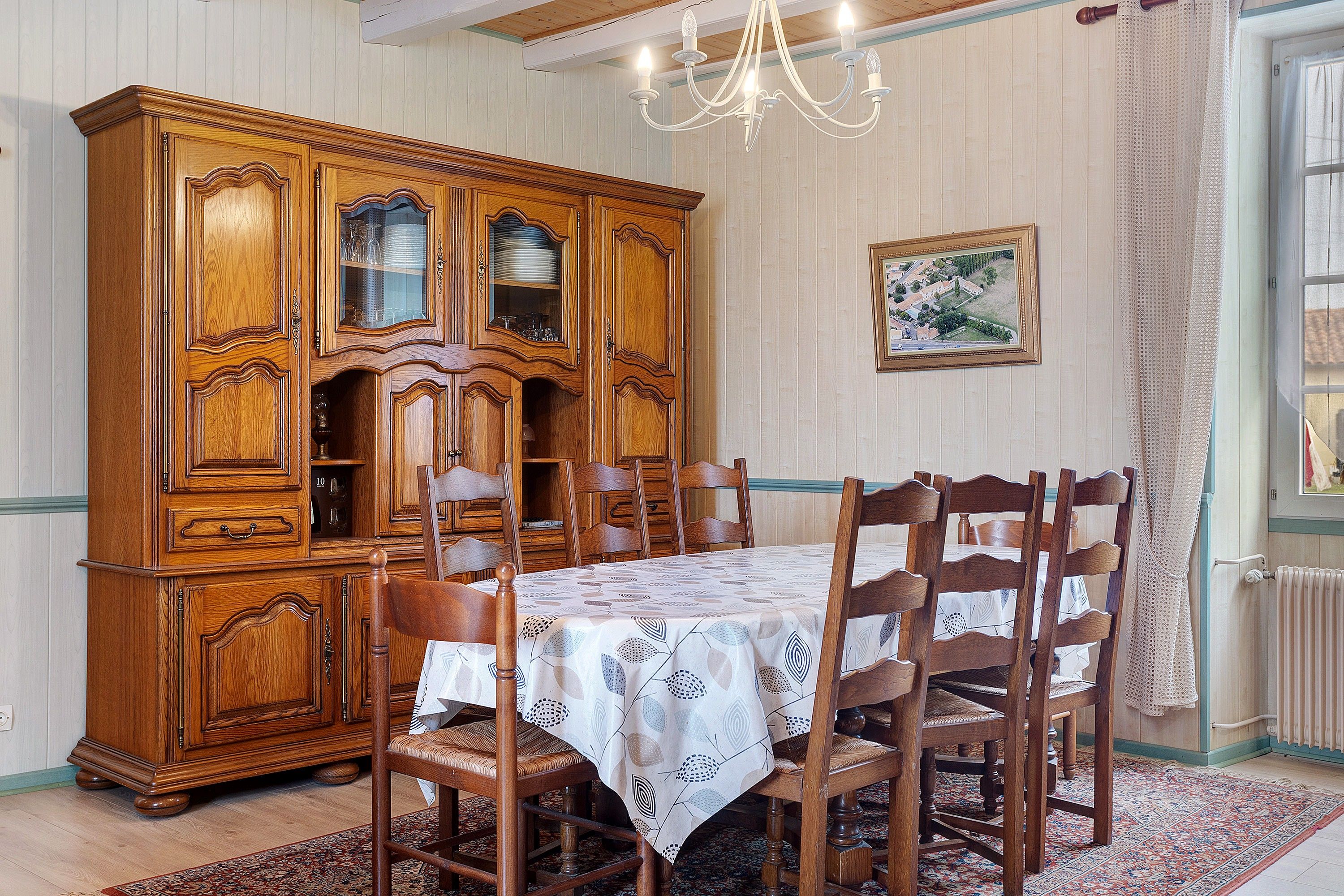 Une salle à manger avec un buffet en bois, une table recouverte d’une nappe et des chaises.