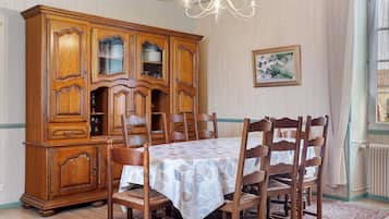Une salle à manger avec un buffet en bois, une table recouverte d’une nappe et des chaises.