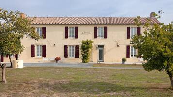 A two-story building with a tiled roof, multiple windows with shutters, and a sign that reads 'Le Paradis.'