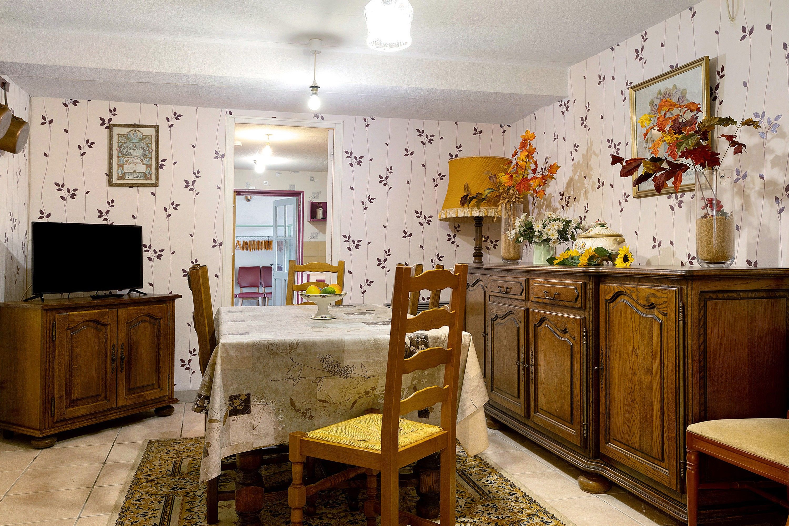 A dining area with a table, chairs, a television, and a cabinet.
