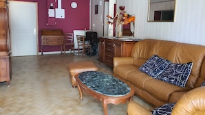 A living room with a brown leather sofa, a wooden coffee table, and a herringbone-patterned floor.