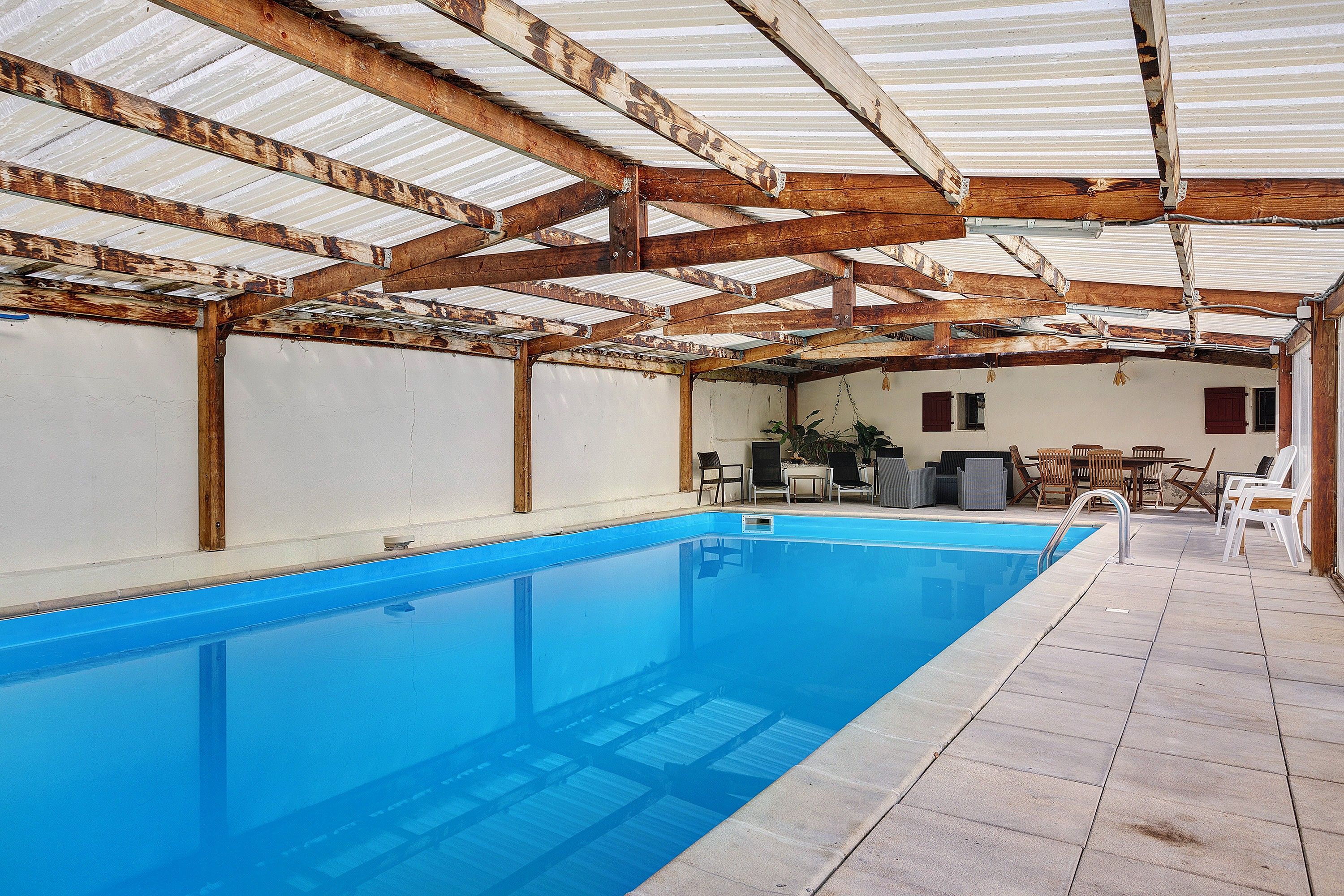 Une piscine intérieure dotée d’un sol carrelé et d’une structure de toit en métal.