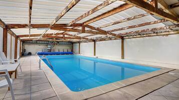 Une piscine intérieure avec un sol carrelé et un escalier métallique.
