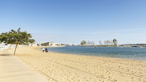 A beach with a wooden boardwalk, a clear sky, and a calm sea.
