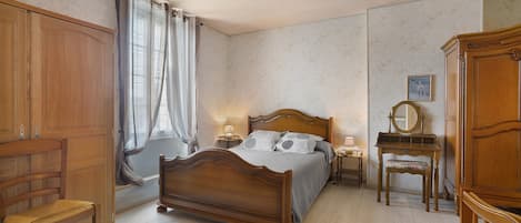 Un dormitorio con una cama de madera, una silla, una mesita de noche, un aparador y un ventilador de techo.