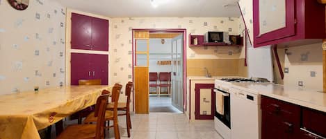 Cozinha compacta com área de refeições, com fogão, micro-ondas e armários.
