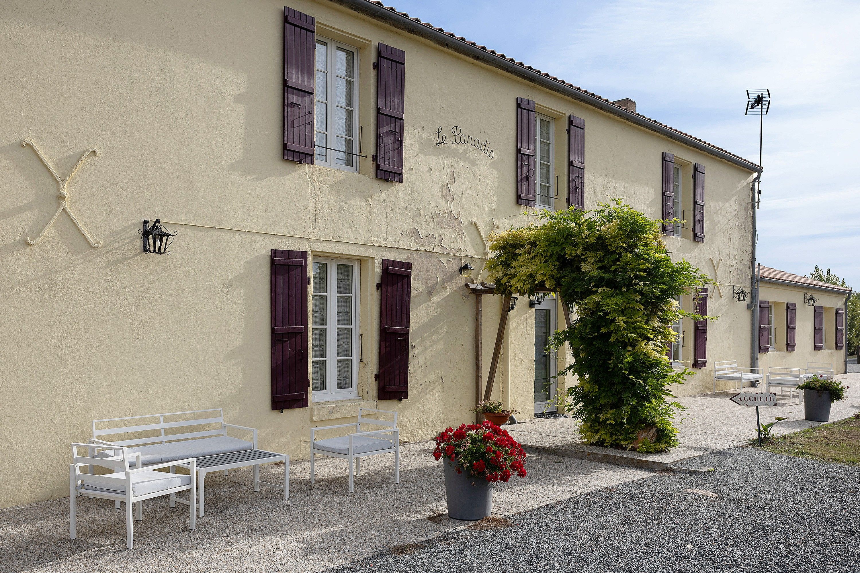 A building with a sign reading 'Le Parcadis' and a sign for 'ACCIETEIL' indicating a business. There are outdoor seating areas with white benches.